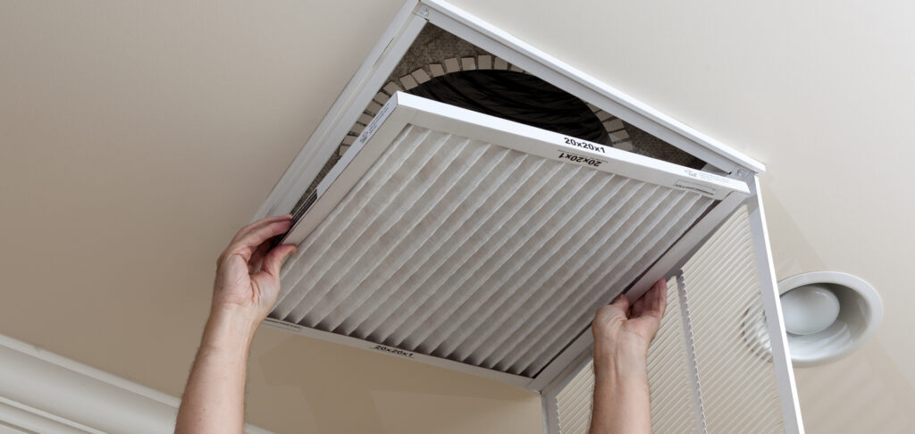 Senior man opening air conditioning filter in ceiling