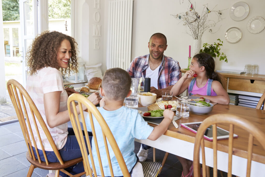 Family At Home Eating Meal In Kitchen Together